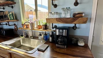 Une cuisine avec des meubles en bois, un évier en acier inoxydable et une machine à café.
