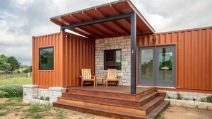 Ein modernes Haus mit Natursteinfassade, großen Fenstern und einer überdachten Veranda mit Stufen.