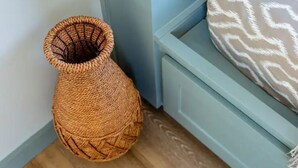 A corner of a room with a woven basket, a light blue wall, and a patterned cushion on a light blue bench. - Tranquility at Odonata Escape --- Chic modern container home in a country setting (Fredericksburg)