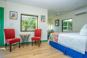 A bedroom with a bed, two red chairs, a small table, and a window. - Happy Boho at Odonata Escape -- Luxurious Shipping Container stay in a rural setting (Fredericksburg)