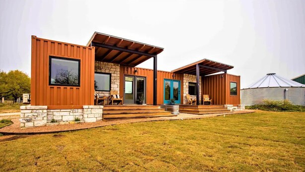 Ein modernes Haus mit Steinaußenwand, Holzverkleidung und einer blauen Tür.
