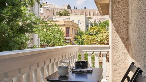 A balcony with a table, a camera, and a cup. - Sleeping with the Ancient Gods in Koukaki (Athina)