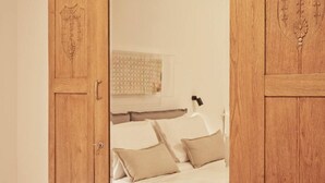 A bedroom with a bed, pillows, a nightstand, and a window with blinds. - Sleeping with the Ancient Gods in Koukaki (Athina)