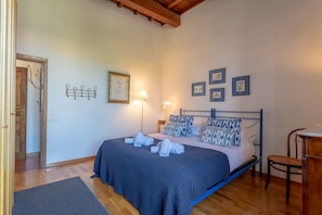 A bedroom with a bed, bedside lamps, a chair, and framed pictures on the wall.