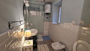 Une salle de bain équipée d’une baignoire, de toilettes, d’un lavabo et d’une douche.