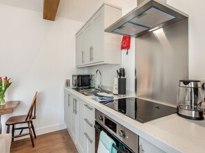 Une cuisine moderne équipée d’appareils électroménagers en acier inoxydable, d’un four à micro-ondes, d’une bouilloire et d’un évier.