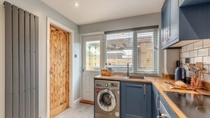 A modern kitchen with a built-in washing machine, a sink, and wooden cabinetry. - 2 bedroom accommodation in Warkworth (Warkworth)