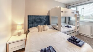 A hotel room with bunk beds, a bedside table with a lamp, and a window with blinds. - 2 bedroom accommodation in Warkworth (Warkworth)