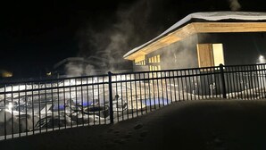 A snow-covered outdoor area with a building featuring a wooden roof and a metal fence. - 2 Bedroom + Sleeping loft condo near mountain village w/shuttle route (Gallatin Gateway)
