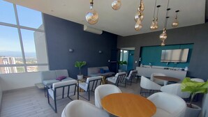 A modern living room with white furniture, a wooden coffee table, and a large window offering a city view. - Great 3 BD Apt in the BEST location in San José, Rohrmoser (San José)