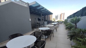 An outdoor patio with round tables and chairs, a covered seating area, and potted plants. - Great 3 BD Apt in the BEST location in San José, Rohrmoser (San José)