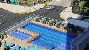An outdoor swimming pool with lounge chairs and umbrellas, surrounded by potted plants. - Great 3 BD Apt in the BEST location in San José, Rohrmoser (San José)