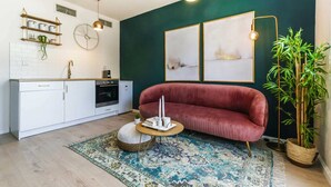 A modern kitchen with white cabinets, a red velvet sofa, and a patterned rug. - Dorot 13 - Studio Apartment, Sleeps 2 (Jerusalem)