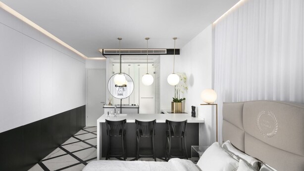 Een moderne hotelkamer met een bed, een zithoek met stoelen, een kitchenette en een badkamer.