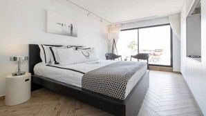 Een moderne slaapkamer met een groot bed, een nachtkastje, een lamp en uitzicht op het landschap door een groot raam.