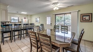 A dining area with a round table and chairs, a ceiling fan, and a view through a sliding glass door.