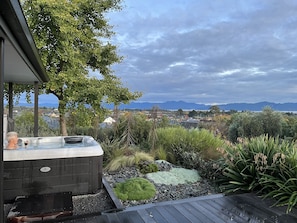 Uma banheira de hidromassagem com vista para montanhas e um jardim.