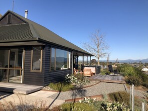 A modern house with large windows, a covered patio, and a view of mountains. - Views over Blenheim - Blenheim Holiday Home (Blenheim)
