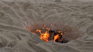 Een strand met een vuurkuil in het zand.