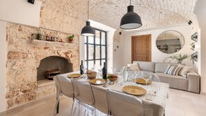 A dining area with a stone wall, a fireplace, and a modern dining set. - Beautifull Villa with Trullo (Ostuni)