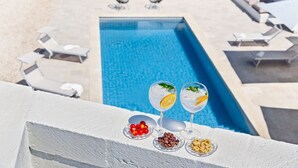 A poolside area with lounge chairs, a pool, and a table with drinks and snacks. - Beautifull Villa with Trullo (Ostuni)