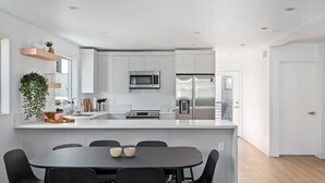 A modern kitchen with white cabinets, stainless steel appliances, and a central island with seating. - Brand new house next to Downtown Los Angeles (Los Angeles)