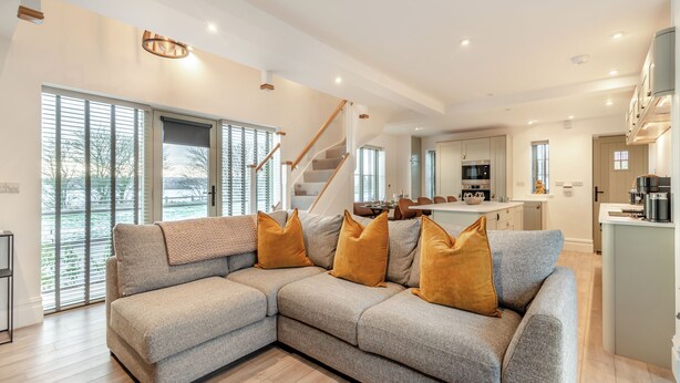 A modern living room with a sectional sofa, a staircase, and a kitchen area. - 3 bedroom accommodation in Scaling Dam, near Whitby (Scaling Dam, near Whitby)