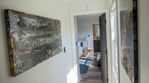 Experience the perfect blend of art and functionality in this stylish hallway, featuring a large abstract painting and a cozy reading nook.