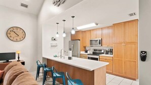 Een moderne keuken met houten kastjes, een centraal eiland en hangende lampen.
