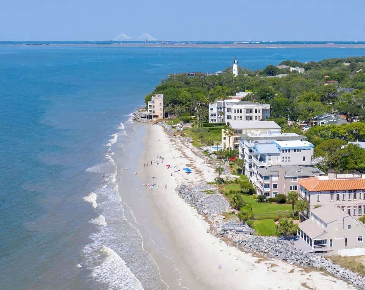 Un hôtel situé sur la côte, avec un accès direct à la plage, plusieurs bâtiments et un phare en arrière-plan.