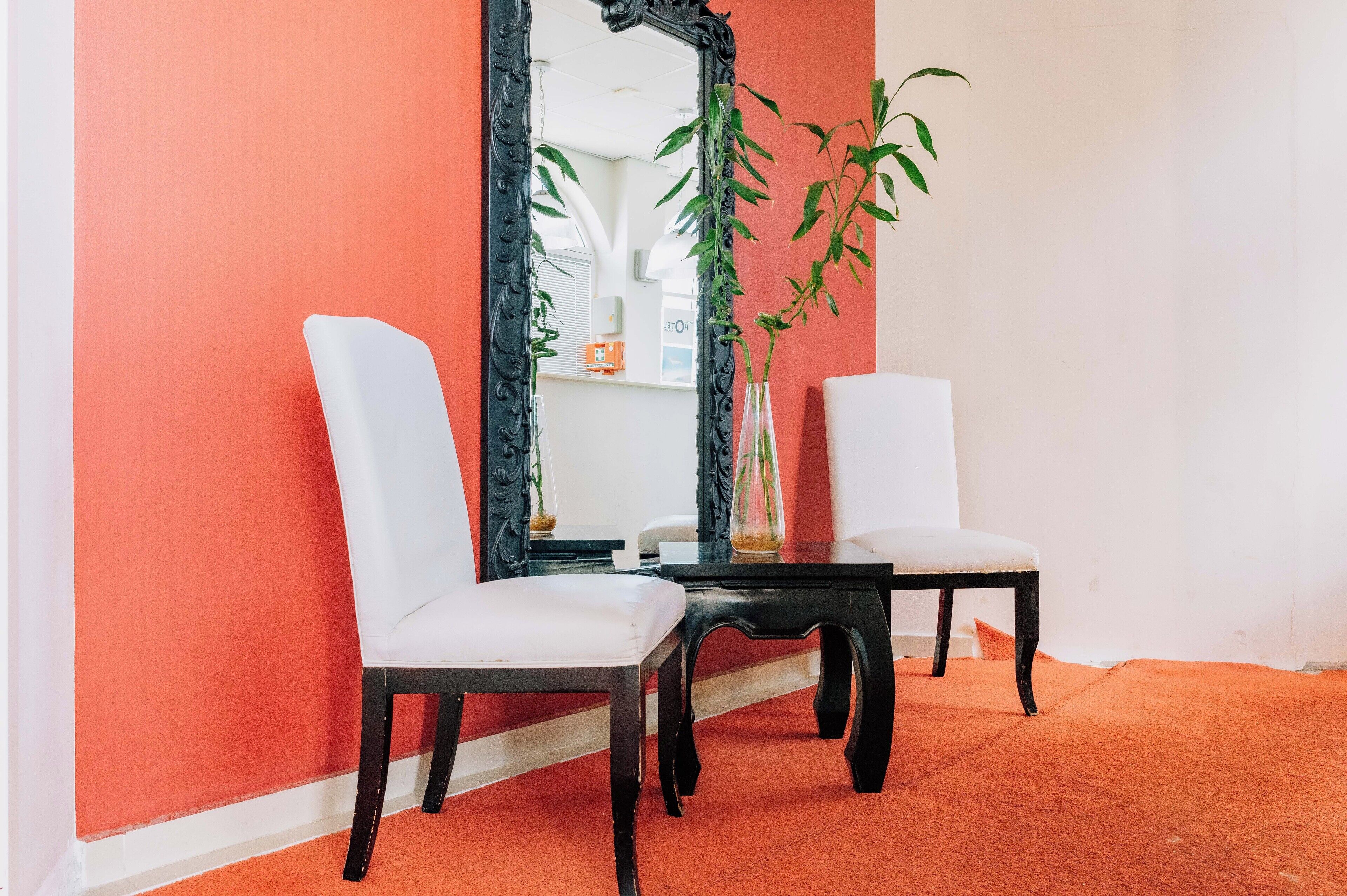 A room with two white chairs, a black table, and a large mirror.