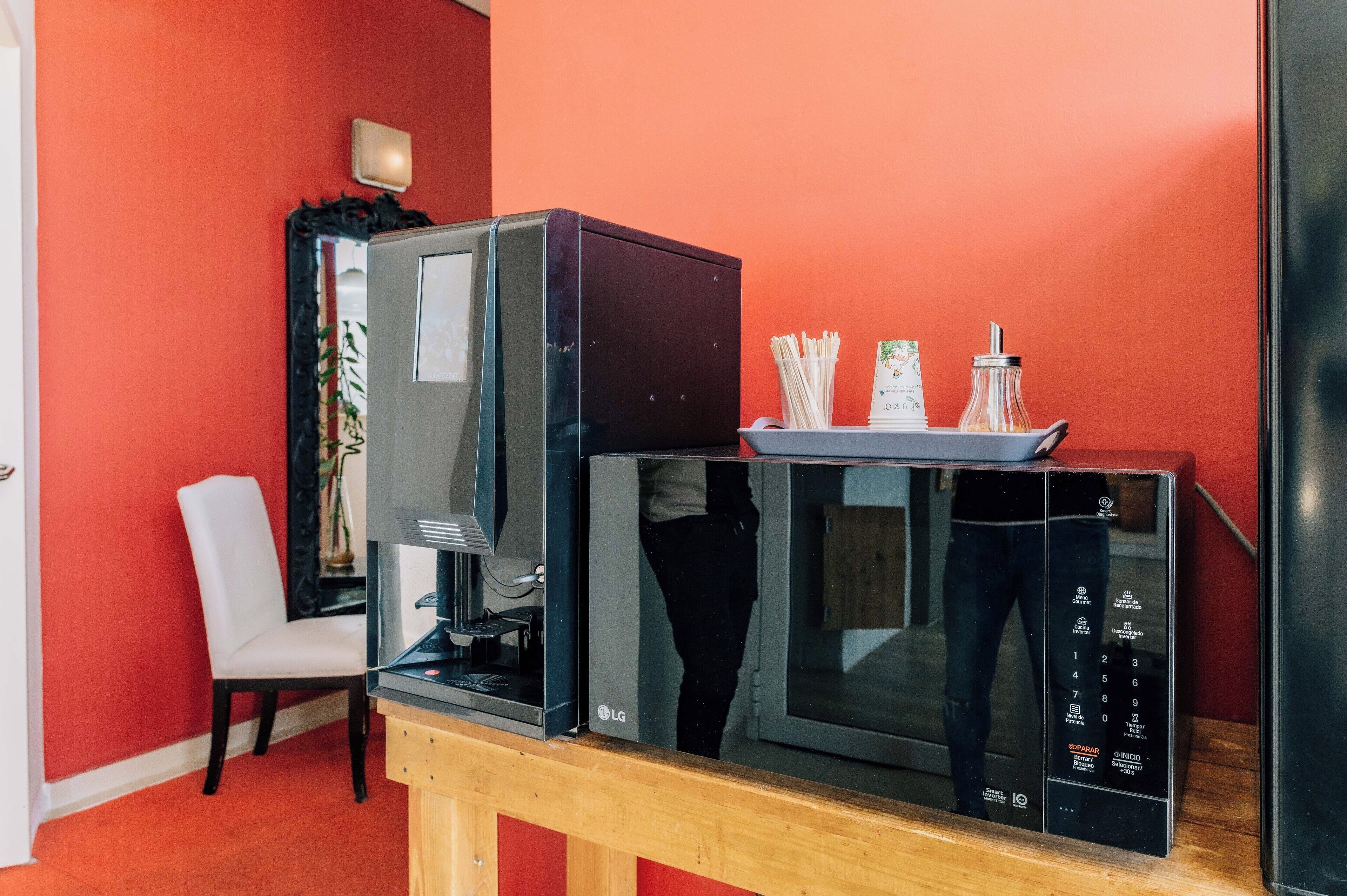 Eine Mikrowelle und eine Kaffeemaschine auf einem Holztisch in einem Raum mit roten Wänden.