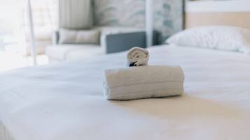 Een keurig opgemaakt bed met een opgerolde handdoek, een kussen en een hoofdbord.