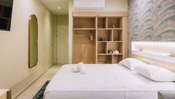 Una habitación de hotel con una cama grande, un armario empotrado, un espejo y un aire acondicionado instalado en la pared.