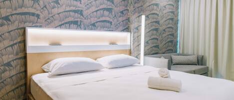 A hotel room with a bed, a headboard, a sofa, and a curtain.