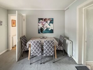 A room with a dining table and chairs, a radiator, and a framed picture on the wall.