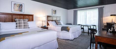 A hotel room with two beds, a desk, and a television.