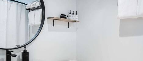 A modern bathroom with a white sink, a toilet, a mirror, and a towel rack.