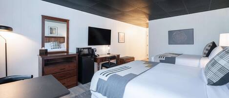 Une chambre d’hôtel équipée d’un lit, d’un bureau, d’une chaise, d’une télévision et d’une petite kitchenette.