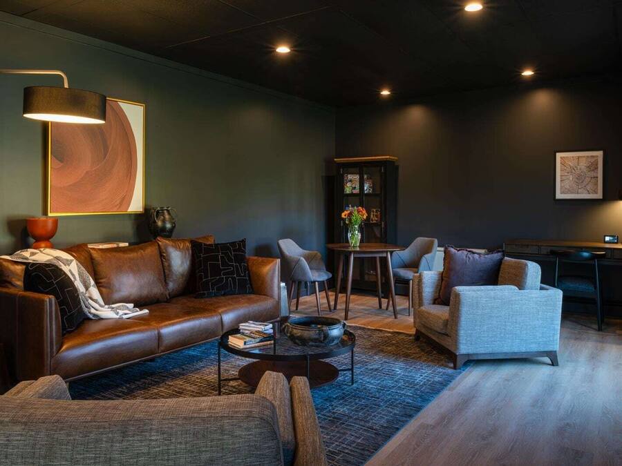 Una sala de estar moderna con un sofá de cuero, sillones, una mesa de centro y una estantería.