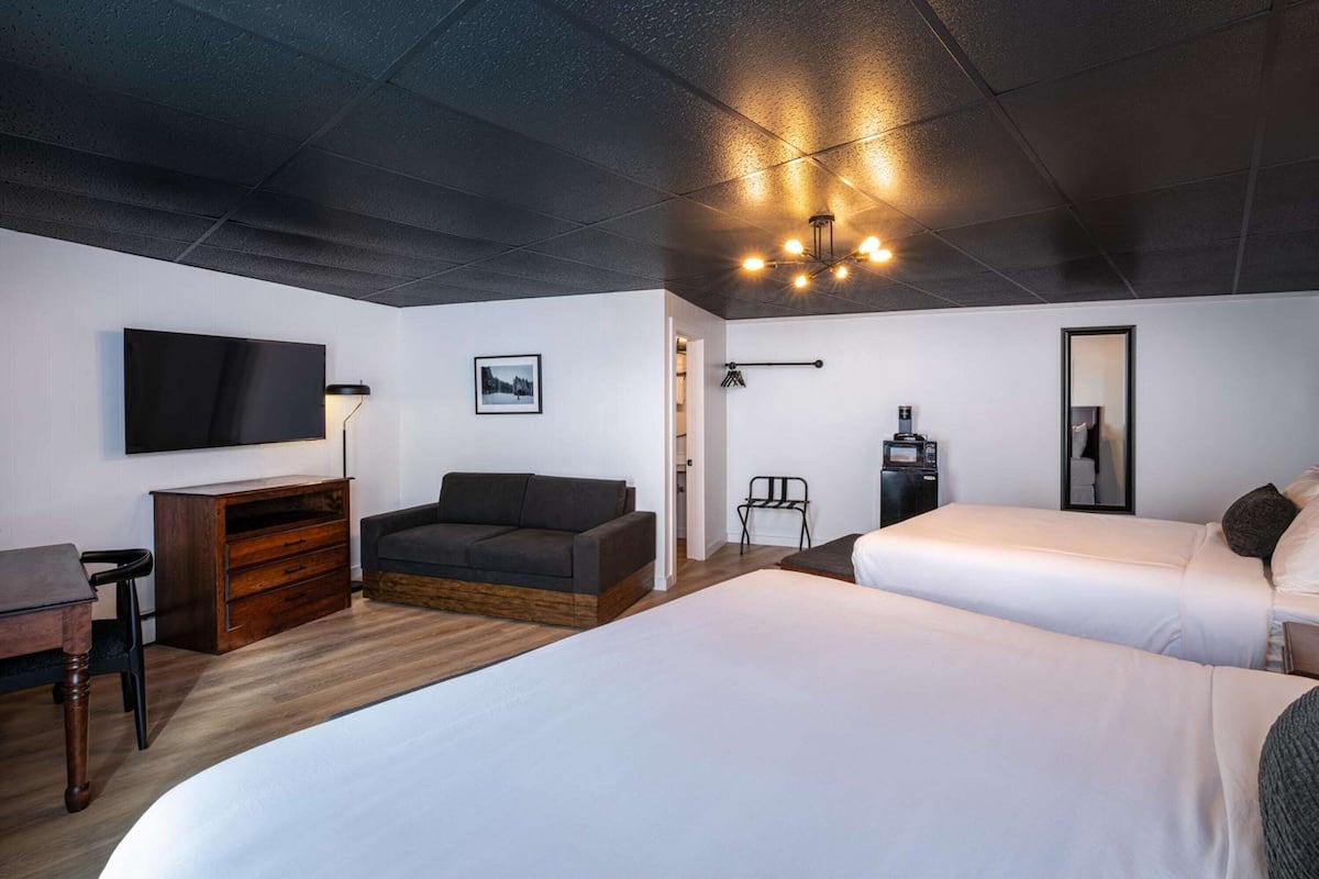 A modern hotel room with a large bed, a sofa, a desk, and a television.