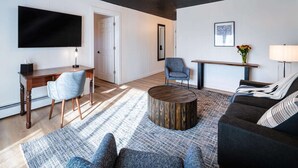 A modern living room with a flat-screen TV, a round coffee table, a sofa, and a chair. - Trailhead by Weekender (Tupper Lake)