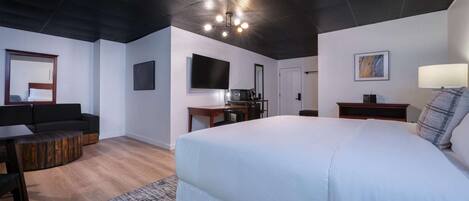 A modern hotel room with a large bed, a flat-screen TV, a desk, and a sofa.