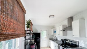 A modern kitchen with white cabinets, a black refrigerator, and a stainless steel oven.