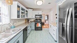 A modern kitchen with white cabinets, a stainless steel refrigerator, and a built-in oven.