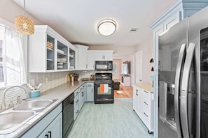 A modern kitchen with white cabinets, a stainless steel refrigerator, and a built-in oven.