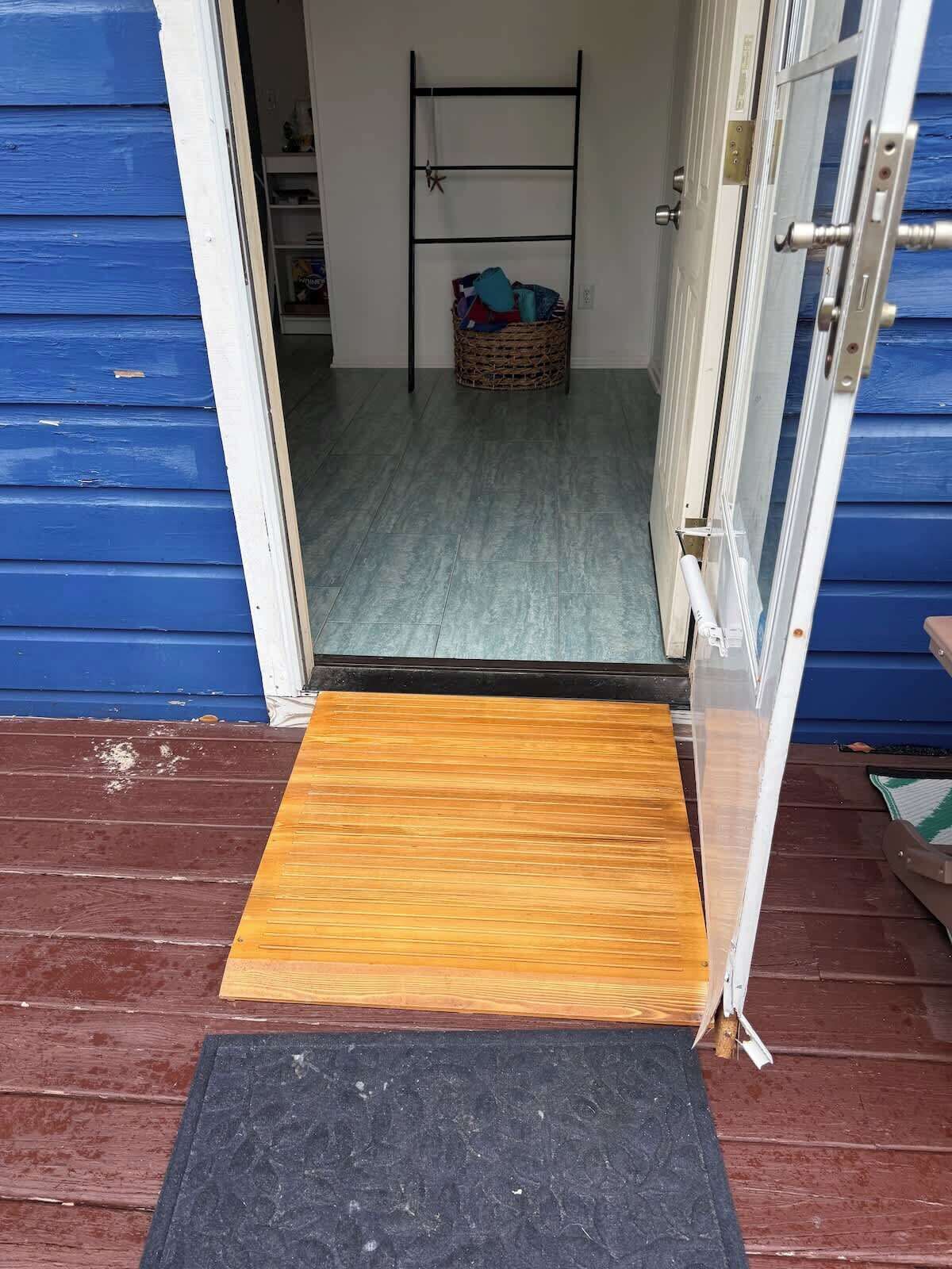 A doorway leading to a room with a metal rack, a wicker basket, and a mat on the floor.