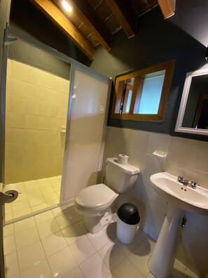Een badkamer met toilet, bidet, wastafel en douchecabine.