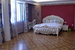 A bedroom with a large bed, a desk, and a chair.