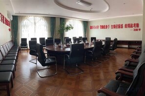 A conference room with a long table and chairs, a potted plant, and a red wall with text.